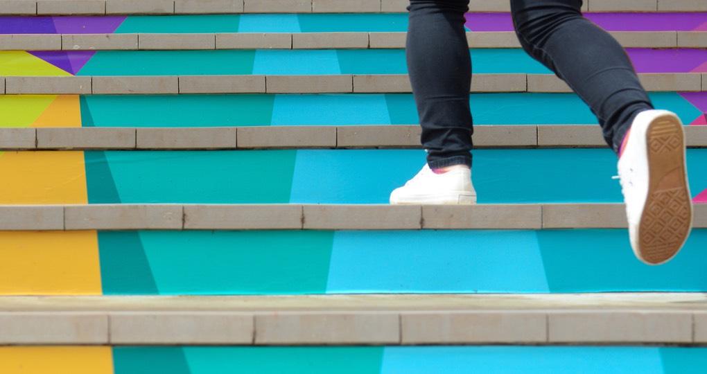Someone taking a step up colourful stairs