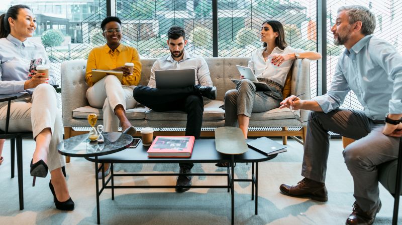 A group of professionals sit in a modern office in discussion.