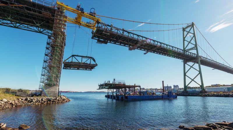 The first section of old deck is lowered from the Angus L. MacDonald Bridge to a waiting barge below, 2017.