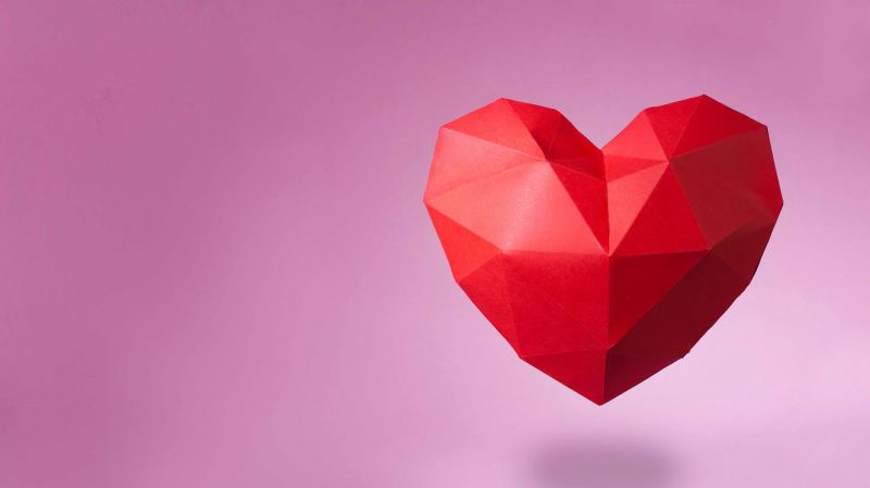 A red paper heart on a pink background. 