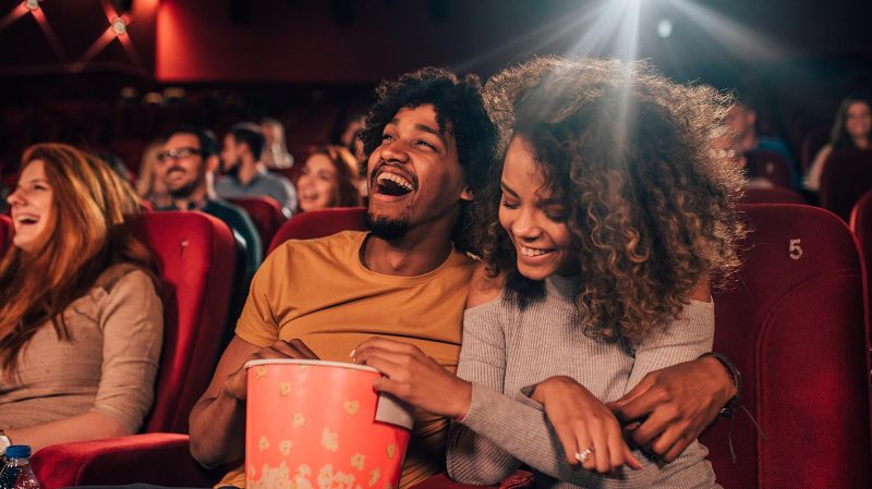 Young couple hugging and eating popcorn at a movie theatre