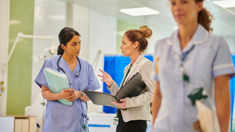 Nurse manager speaking to a nurse holding files in a hospital room