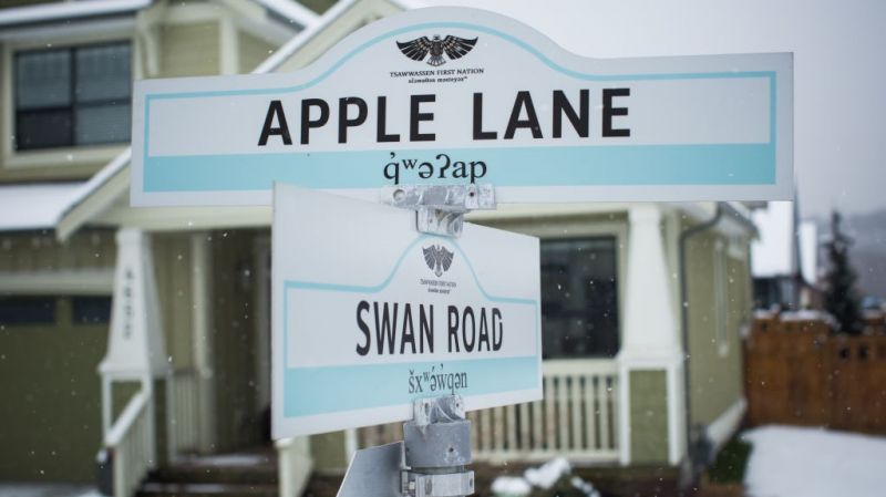 Road signs with inscriptions in different languages ​​on the background of a residential building