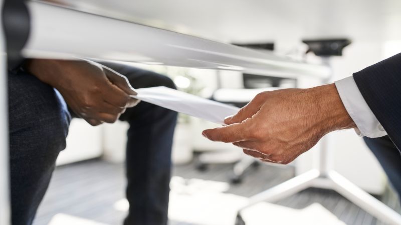 Business people exchange a note under the table