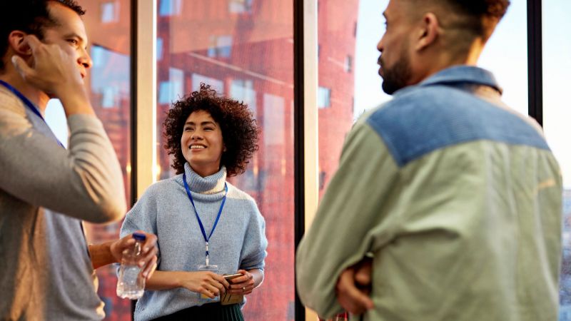 Diverse group of business professionals networking at an event in an urban setting.