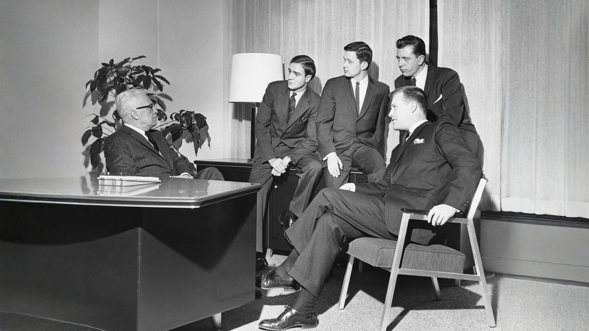 1950s style black and white photo of men in an office meeting