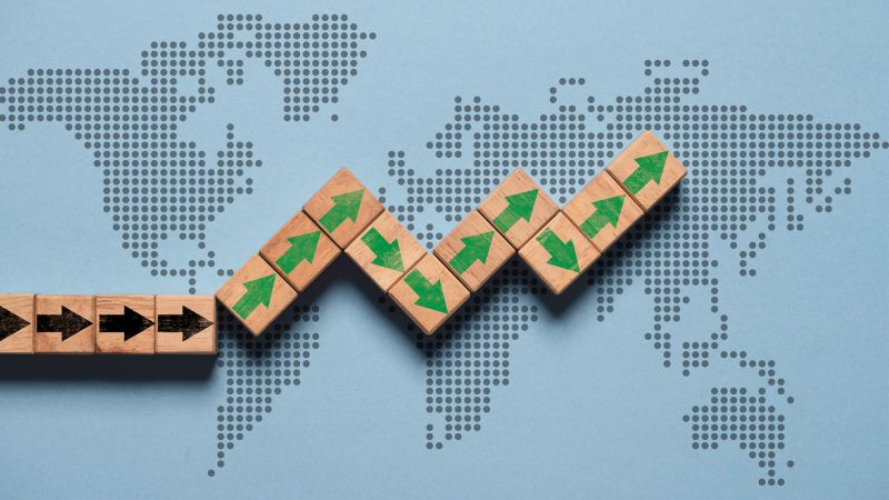 Upward growth arrows on wooden block cubes on top of world map. Global economic growth concept