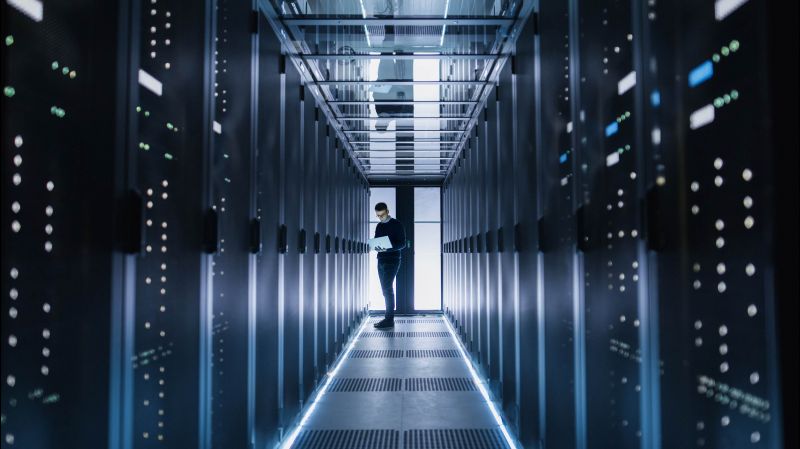 Male IT engineer works on a laptop in a big data centre. 