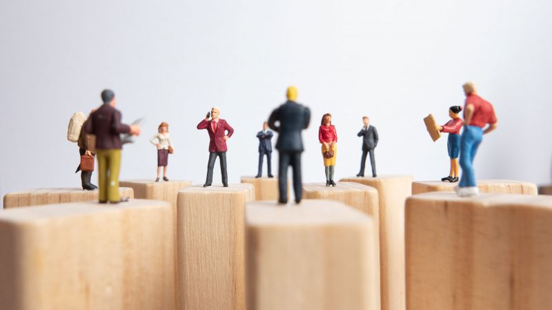 Side view of miniature toys standing on wooden block - social distancing, teamwork concept.