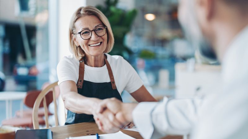 Business owner shaking hands with buyer of their business.  Caption