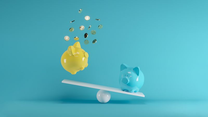 Blue and Yellow piggy banks playing on seesaw. Yellow piggy bank and its coins in mid-air.