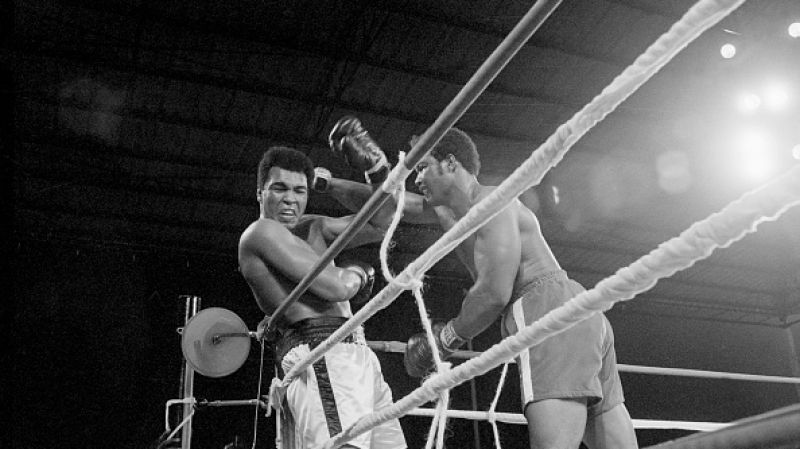 George Foreman punching Muhammad Ali by the ropes.