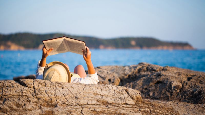 Young woman reading book on a seacoast