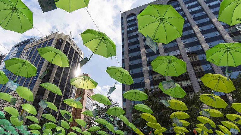 Green umbrellas and modern business architecture over Cheonggyecheon stream in Seoul, South Korea.