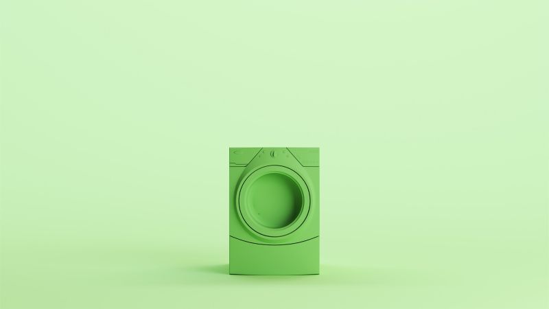 Green washing machine on a mint background
