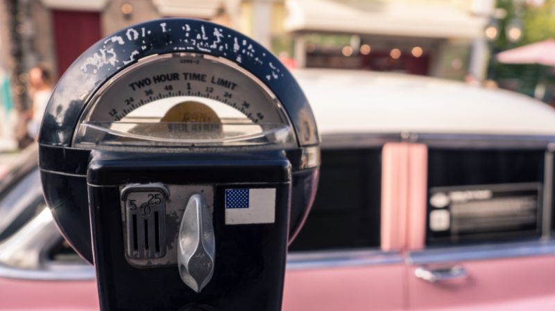 Old parking meter and a vintage car in the background.