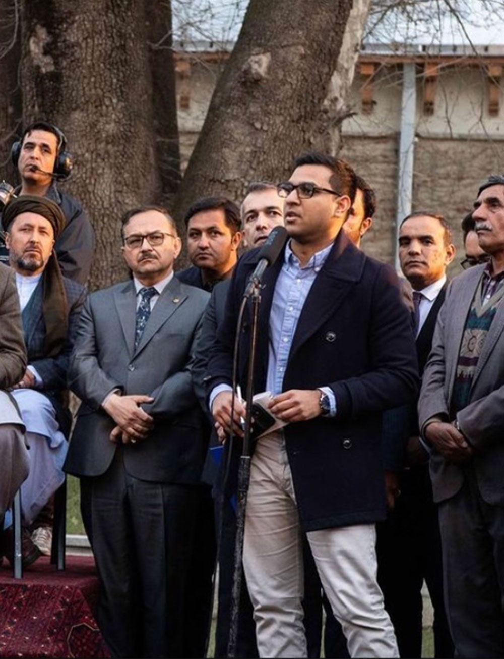 Idrees Ali stands in front of a microhpone at a press conference in Kabul, Afghanistan during the Taliban–U.S. peace deal signing. In the background are people in professional attire and other journalists.