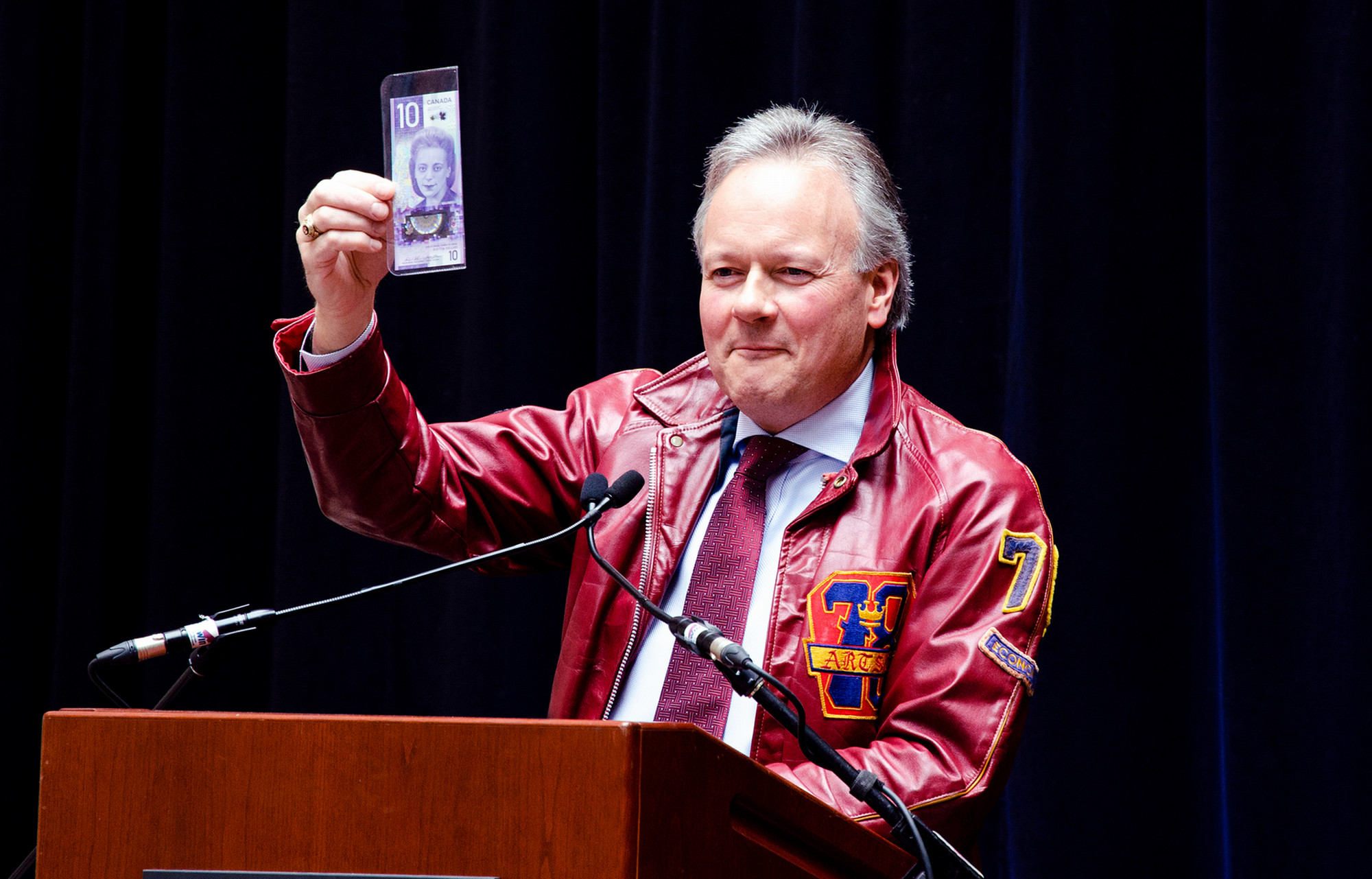 Stephen Poloz, at Goodes Hall in March, shows off the then just-released new version of the $10 bill. He’s wearing the Queen’s jacket he got for Christmas in 1974.