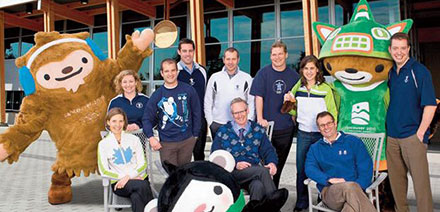 QSB alumni on the VANOC Team in their 2010 apparel, from left: Leah Walton, Mary Thomson, Benjy Berger, Chris Gear, Dick Vollet, John McLaughlin (seated) Don Ford, Katrina Galas, Mike Wilkinson (seated) and Shane Holland, with Olympic mascots Quatchi (far left), Sumi (right) and Miga (front).