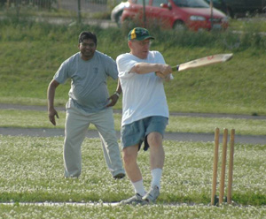 Professor Julian Barling bats while wicketkeeper Jitendra Sahu (EMBA 2010) looks on at the QSB Cricket Challenge