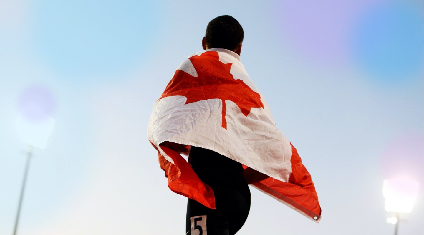 Male athlete with a Canadian flag draped around shoulders