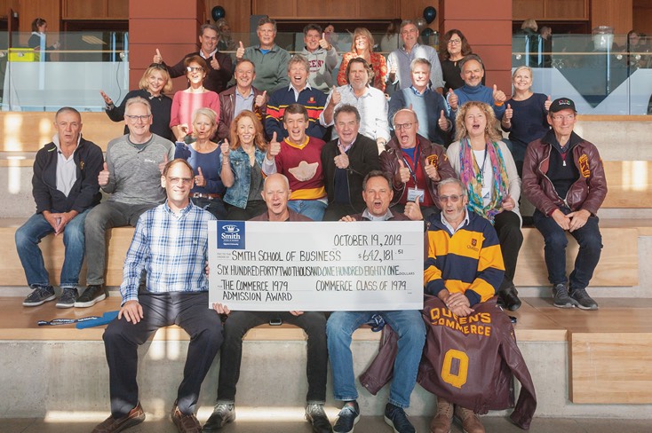 A group shot of Commerce alumni of 1979 holding a cheque for $642,181